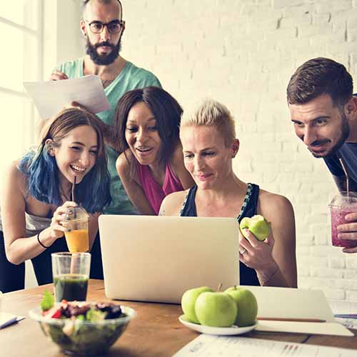 A happy group of co-workers looking at a laptop | Orange Naturals
