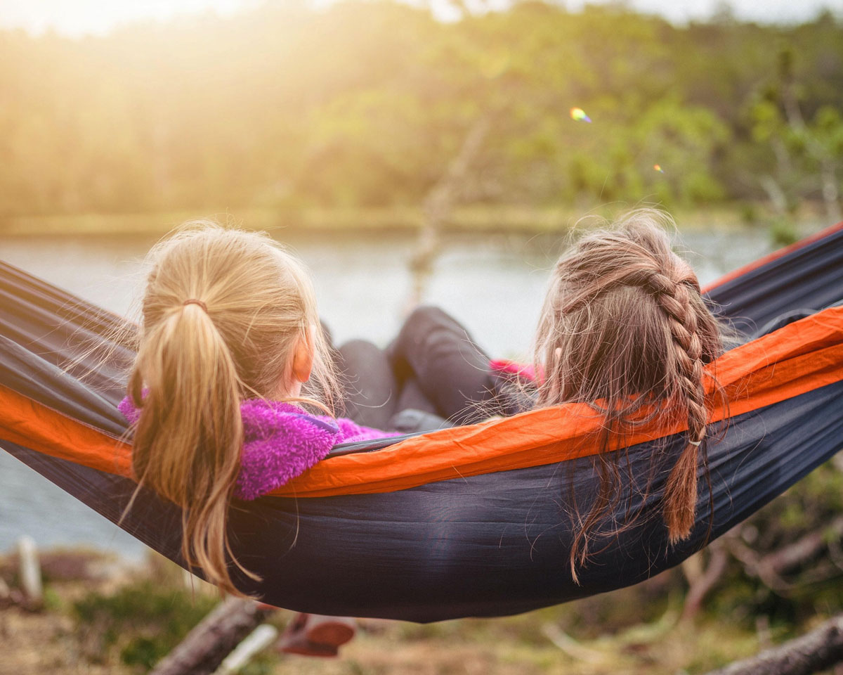 two kids in a hammock looking at a lake