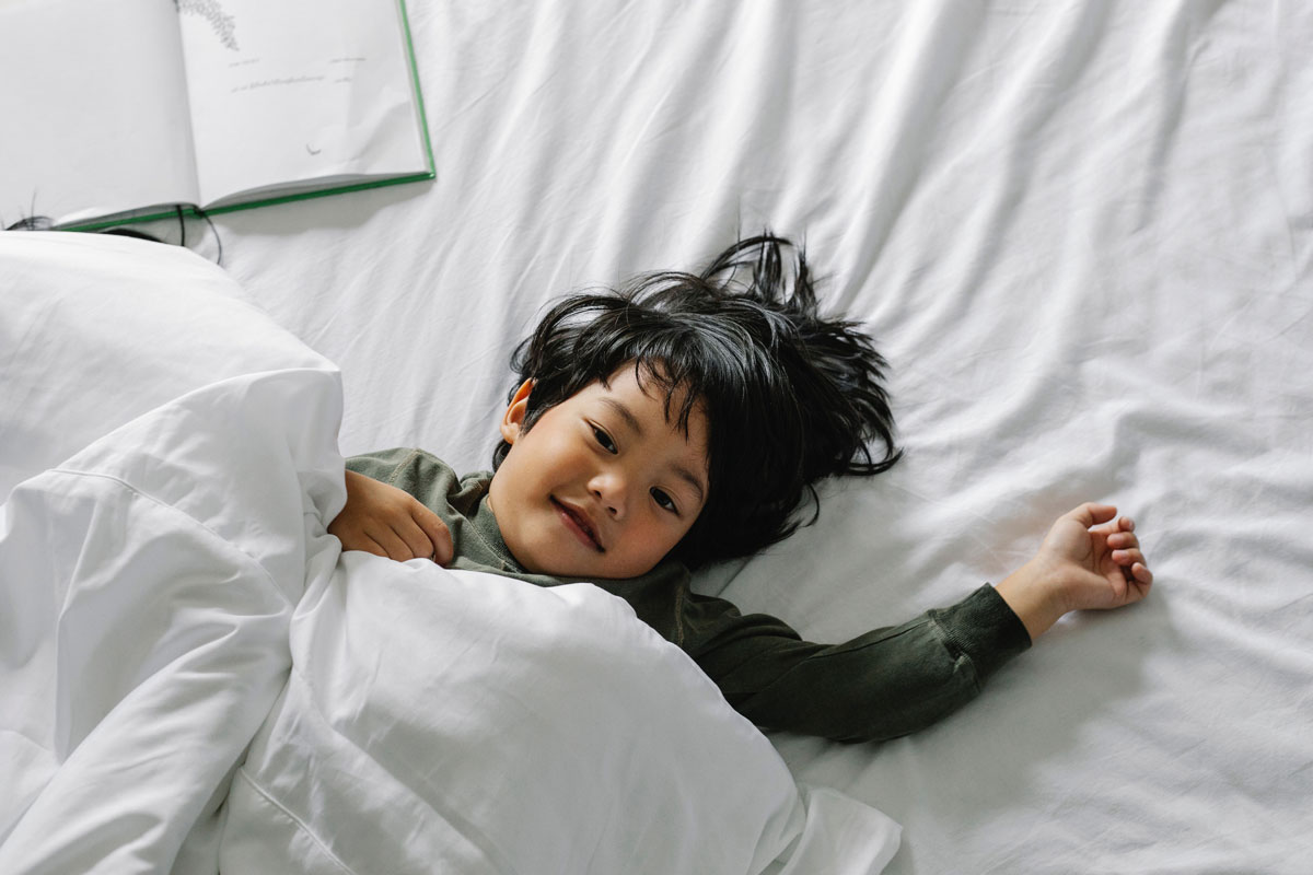 A young boy lying down on a bed