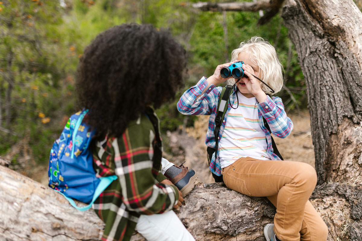 Kids playing in the woods with binoculars