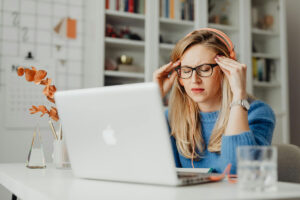 Woman sitting in front of laptop with a headache