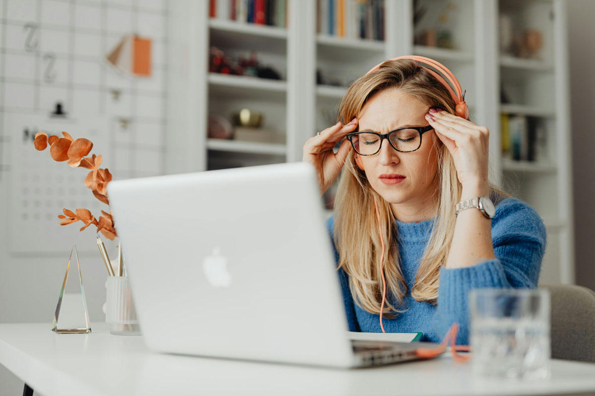 Woman sitting in front of laptop with a headache