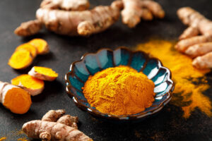 A bowl of turmeric spices & turmeric roots