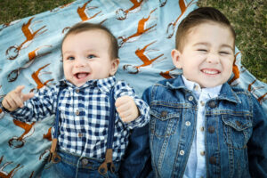 Toddler and kid laying next to each other smiling