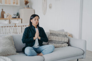 Woman sitting on sofa doing breathing exercises