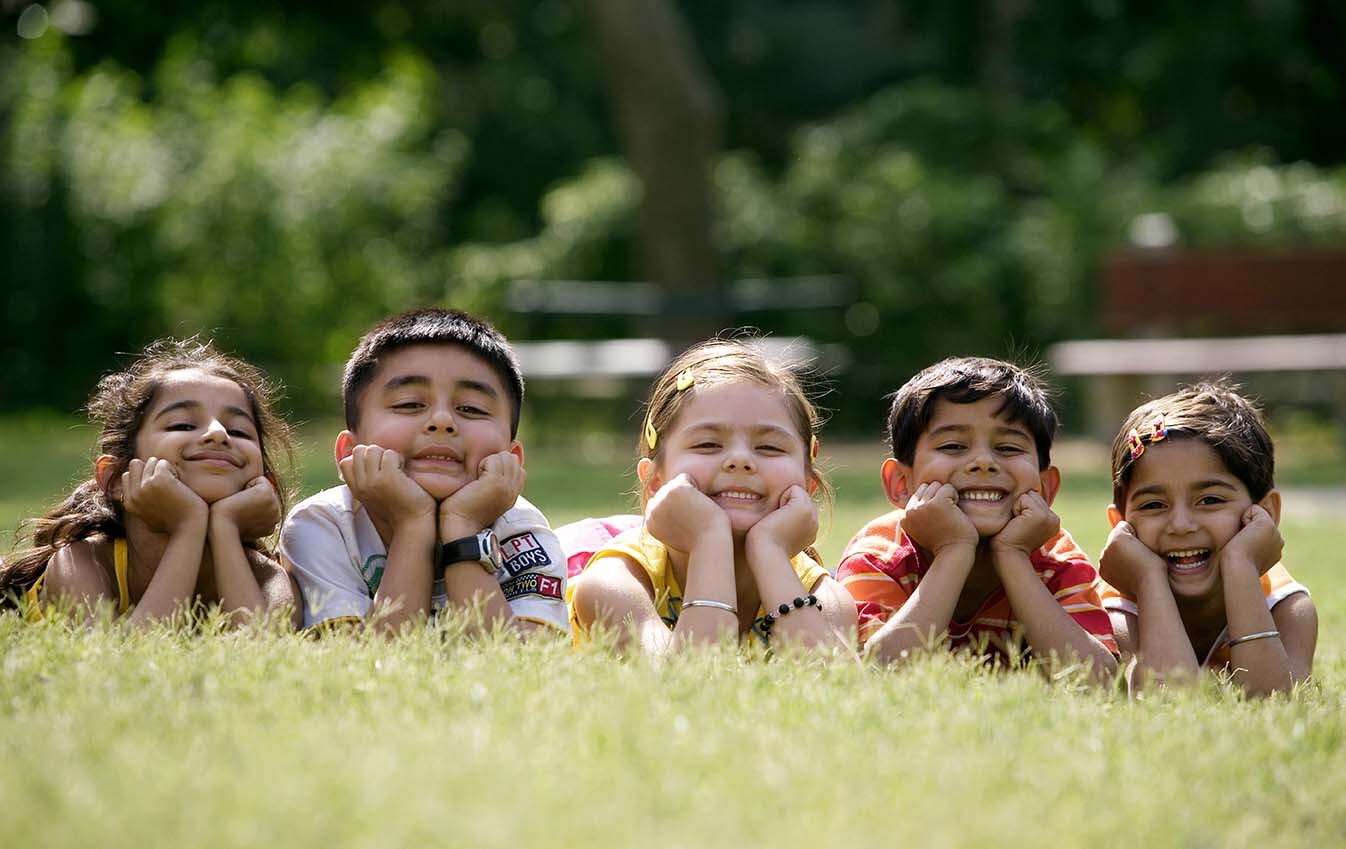 5 children lying on the grass smiling