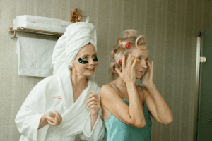 Two women doing skin care in the bathroom mirror