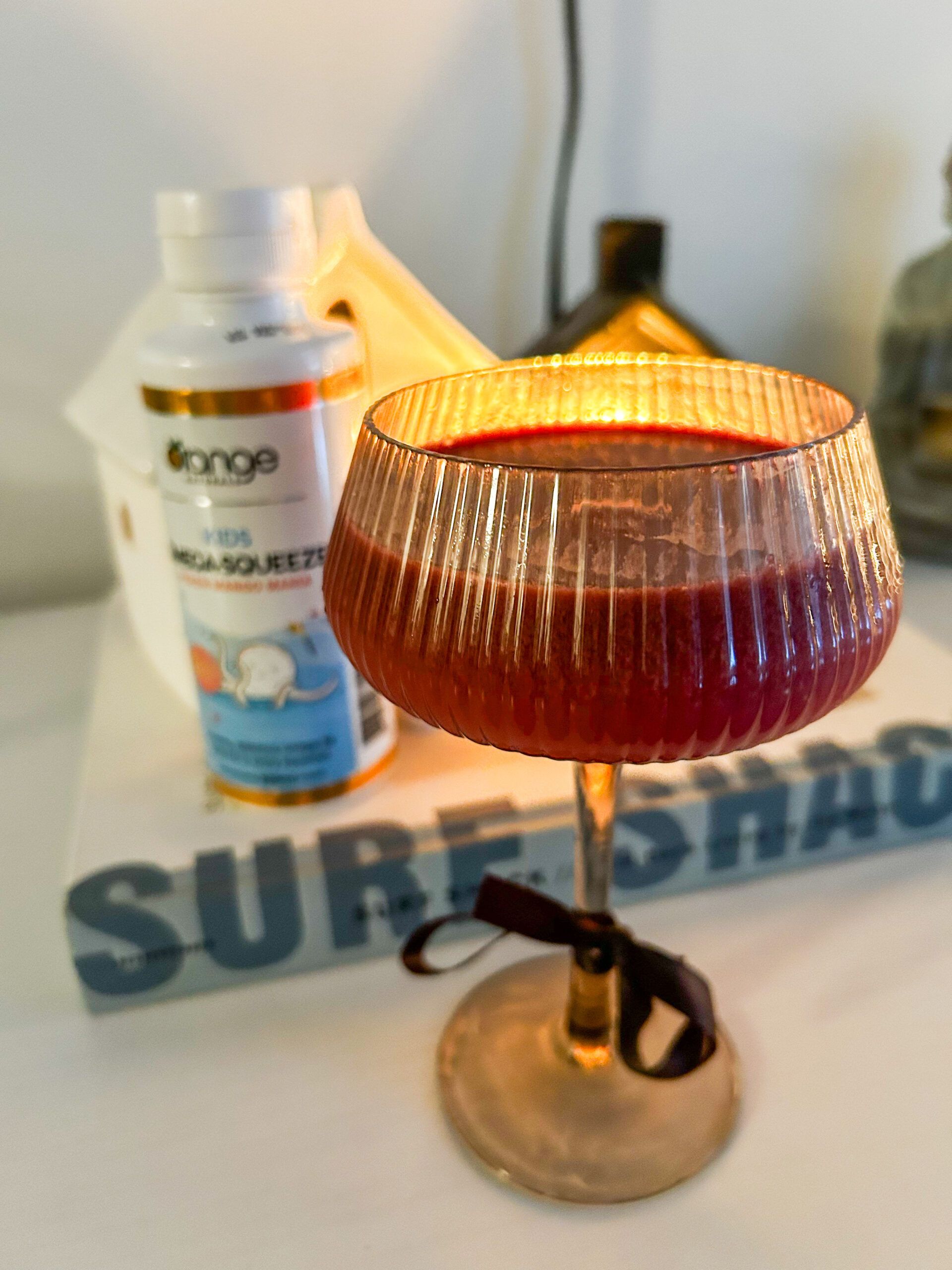 A glass of Pomegranate Fizz with a Kids Omega-Squeeze bottle.