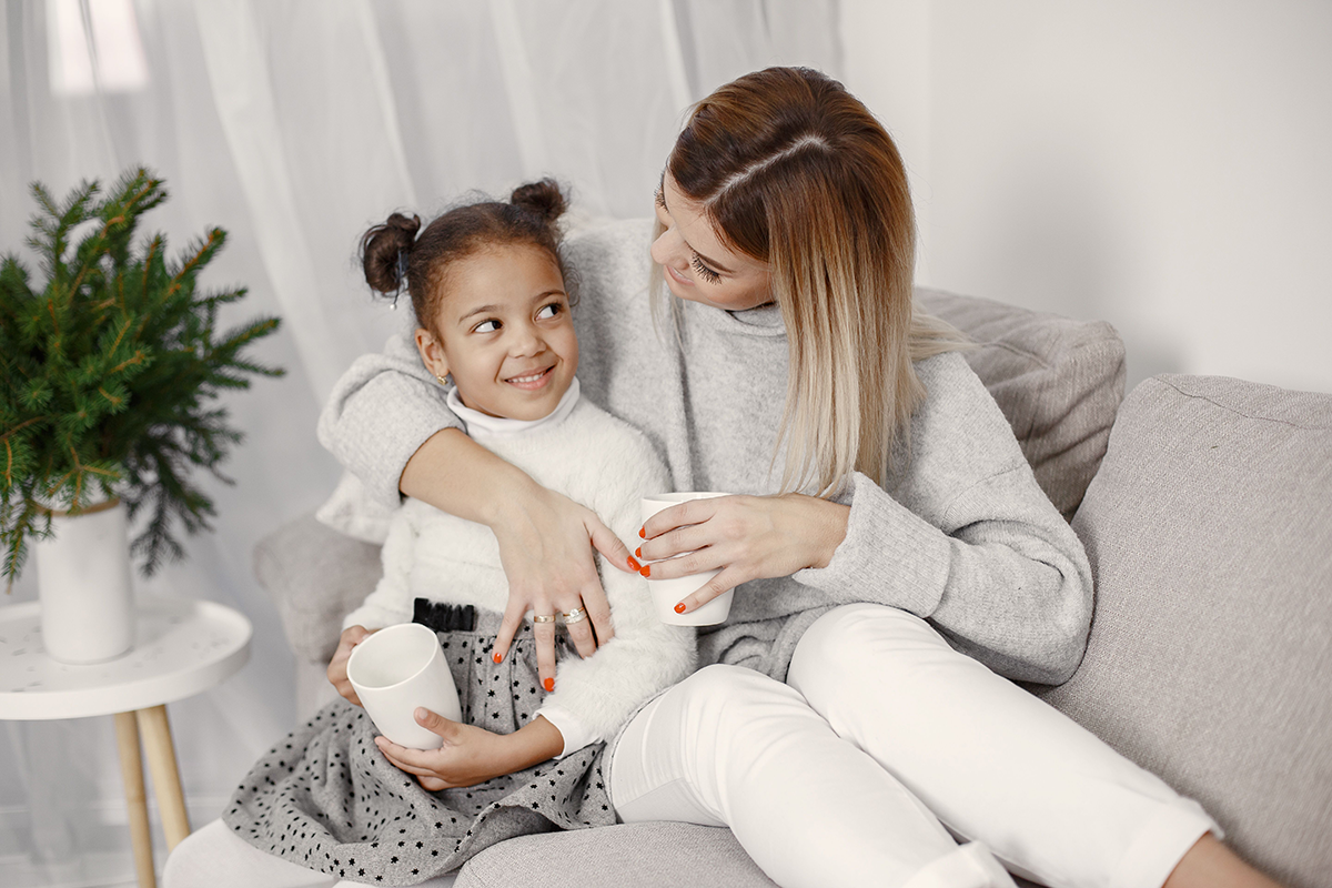 Mom and daughter sitting happily on couch